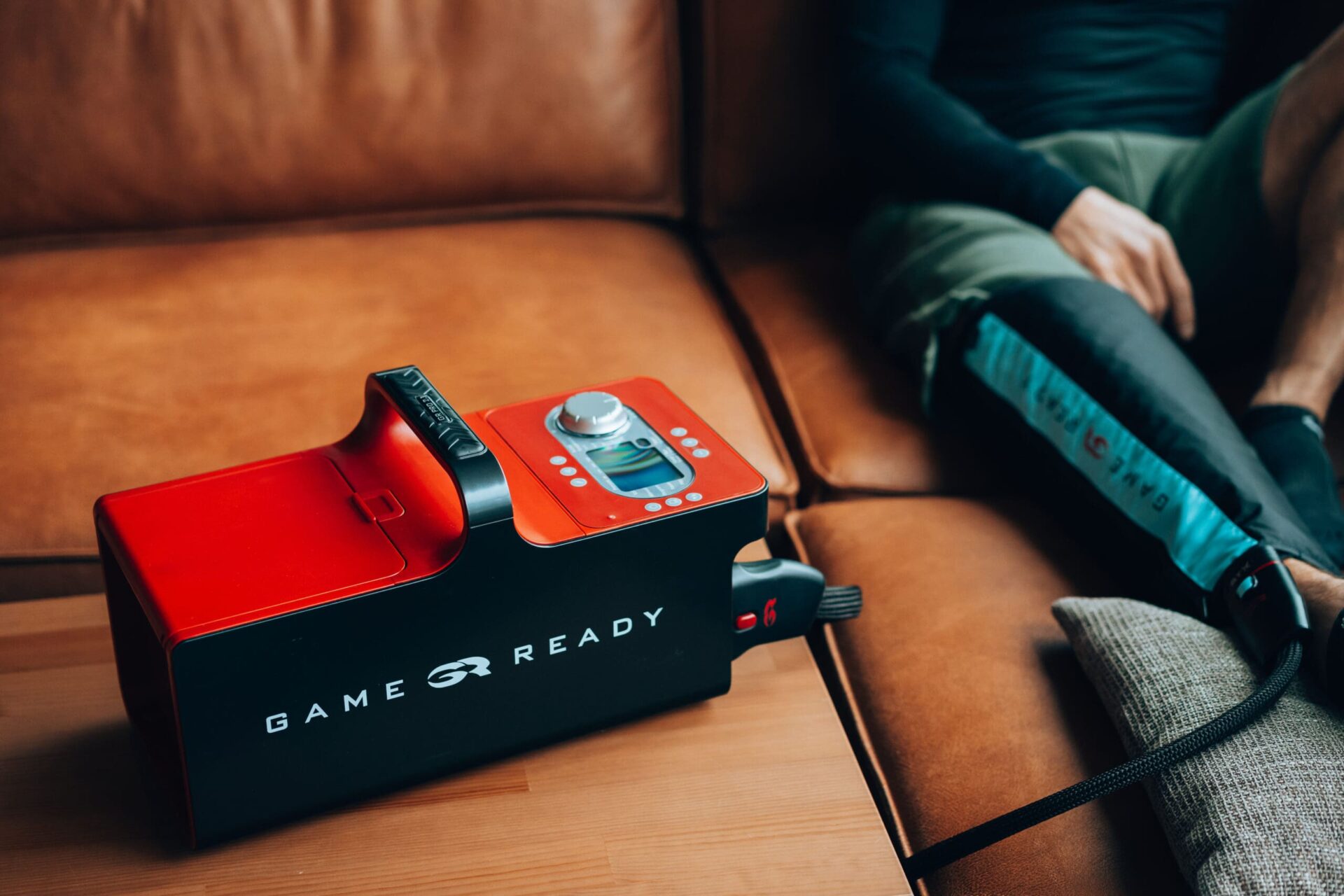 Stoswelle2 Ein Mann sitzt auf einer Couch und kühlt das rechte Bein mit dem Game-Ready System.